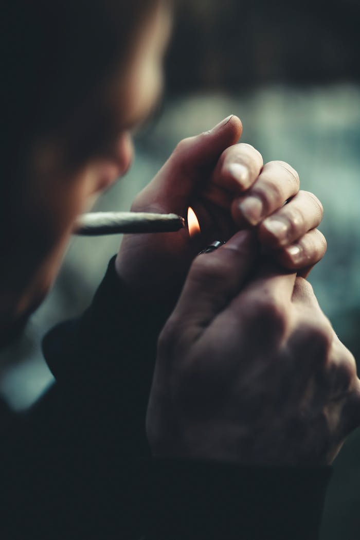 Close-up photo of a person lighting a cigarette with a lighter, focused on hands.